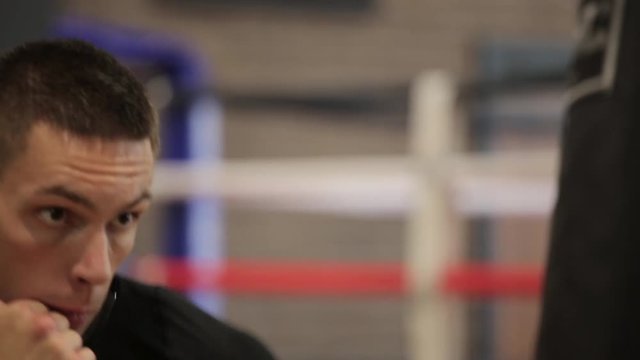 Strong man boxing using punch sake in gym, sunlight, close-up.