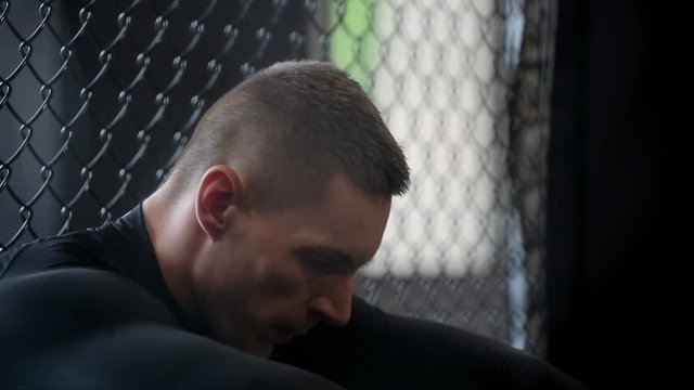 Exhausted Muscular fighter in Sweat, Tries to Catch a Breath in cage at gym