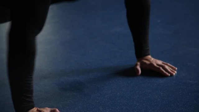 Man doing push-ups in gym, blue background, close-up