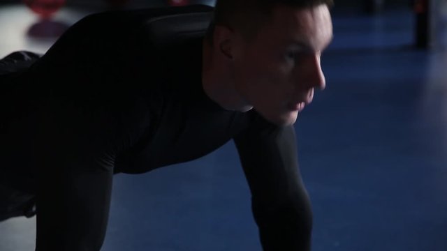 Man doing push-ups in gym, blue background, close-up
