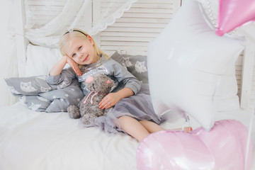 Girl in a beautiful outfit is lying on the bed with a plush cat