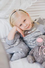 Girl in a beautiful outfit is lying on the bed with a plush cat