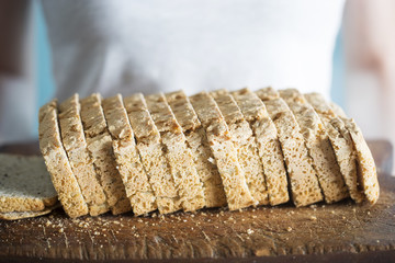 Woman holding gluten free bread with chickpea, linseed, oat, potato, rye flour on wooden board 