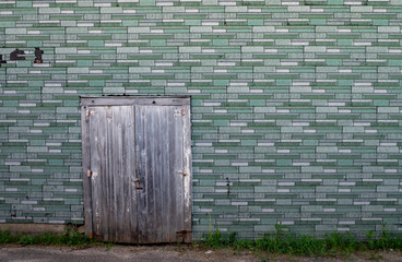 Fototapeta na wymiar Old green and white wall with grey wooden door