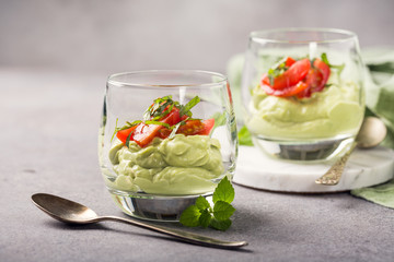 Fresh green avocado mousse with cherry tomatoes in glasses. Healthy vegan food concept with copy space.