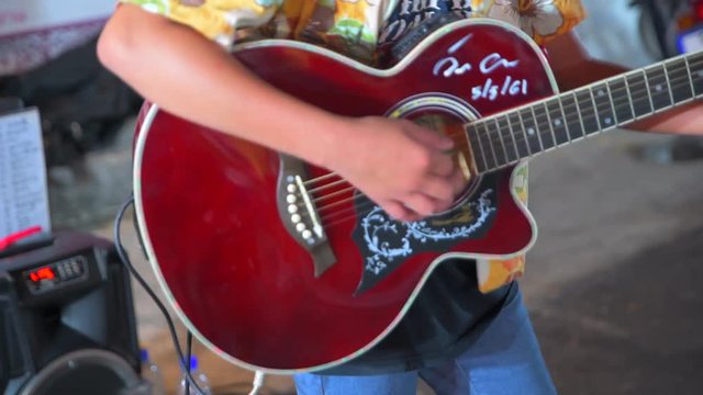 4k Movie Closeup shot of Street guitarists. Musicians are playing on guitars. Close-up of fingers pressing the strings of the instrument in Chinees Walking Street, Bangkok, Thailand