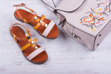 Fototapeta na wymiar Fashionable women's sandals and backpack on white wooden background.