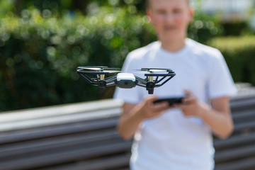 A teenager boy starts a quadrocopter from a smartphone and takes a nature shoot for his video blog. Flying robot drone. Robotics and programming. STEM education.