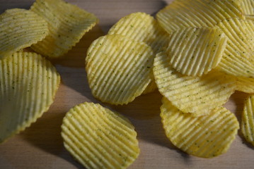 Potatoes fried wavy, embossed, potato chips with sour cream and greens, facies on a wooden board
