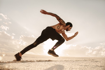 Man accelerating in to sprint on sand dunes