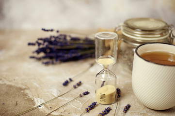 cup of hot lavender tea. Herbal tea hot drink with sand glass timer..