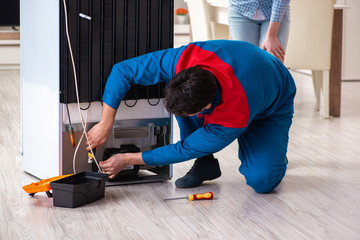 Man repairing fridge with customer