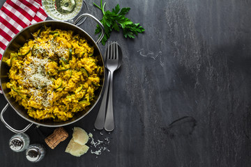 Italian dish yellow Risotto milanese with saffron, zucchini and Parmesan cheese on a black slate...