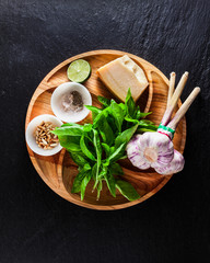 fresh ingredients for cooking Italian classic green pesto basil sauce. with pine nuts, garlic and parmesan cheese. on a black slate table