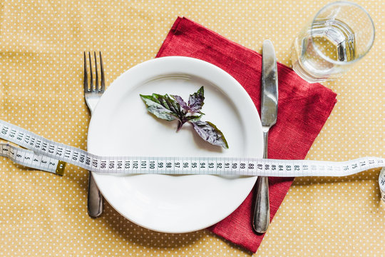 Red basil leaves on a plate together with a measuring tape. The concept of diet, lose weight.