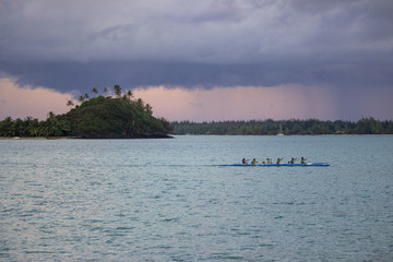 Paddlers in Outrigger Canoe Under Large Cloud at Sunset in Bora Bora