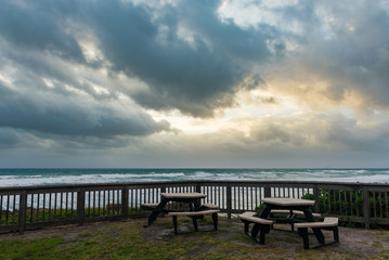 Fototapeta na wymiar two picnic tables overlooking the ocean