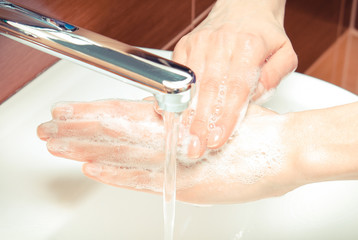 Fototapeta premium Washing of hands with soap under running water in bathroom, hygiene concept