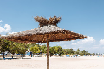 Straw and wooden umbrella on an empty beach background, Sunny day, isolated place for text