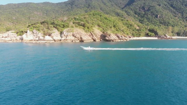 Boat sails along the rocky shore