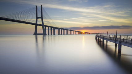 Vasco da Gama-brug en pier over de rivier de Taag in Lissabon, Portugal, bij zonsopgang.