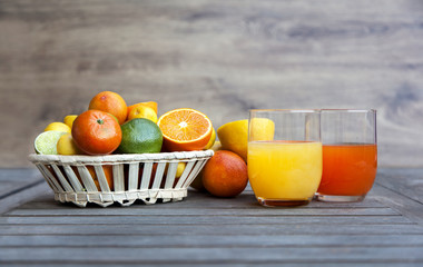 Citrus fruit and juice in a wooden background. Oranges, limes, Tangerines, Chinese oranges, blood oranges and other varieties. High source of vitamin C.