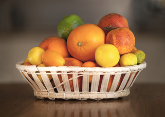 Oranges, limes, t angerines, Chinese oranges, blood oranges and other citrus varieties in a fruit basket.