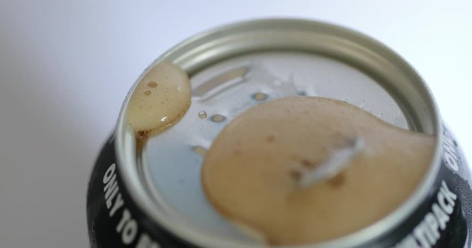 A cola can being opened and fizzing over.