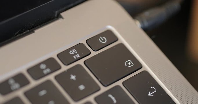 A laptop power button being pressed close up.
