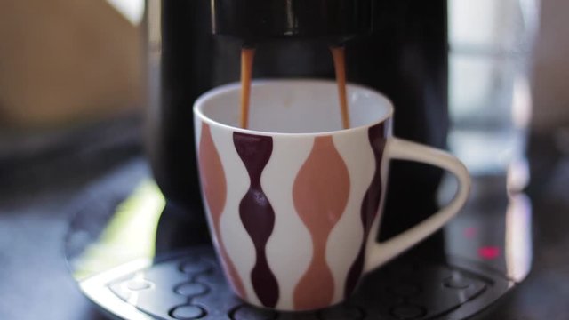 A Coffee-machine making Coffee, and filling it in a Coffee Cup.