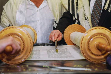 A praying man with a tefillin on his arm and head, holding a Torah, while reading a pray at a...