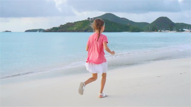 Sihouette of little girl walking on the beach at sunset.