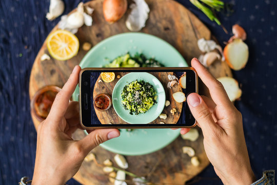 Smartphone food photography of vegetarian lunch or dinner. Woman hands taking phone photo of food in trendy style for social media or blogging.