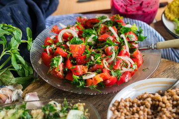 Healthy raw vegetables salad with tomatoes, onion rings, green herbs and spices garnished with...