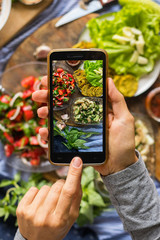 Smartphone food photography of vegetarian lunch or dinner. Woman hands taking phone photo of food in trendy style for social media or blogging.