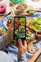 Smartphone food photography of vegetarian lunch or dinner. Woman hands taking phone photo of food in trendy style for social media or blogging.