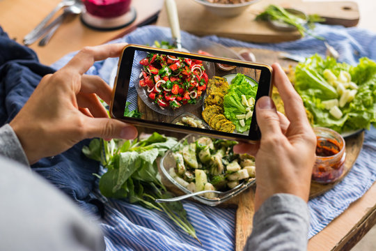 Smartphone food photography of vegetarian lunch or dinner. Woman hands taking phone photo of food in trendy style for social media or blogging.