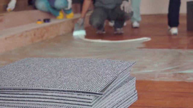 Construction Worker Applying Glue To Floor. Installing Carpet Tiles.