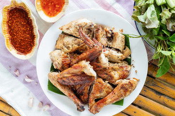 Top view of grilled chicken in white plate on bamboo background
