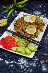Fototapeta na wymiar Thai fried rice with egg on top served with vegetables - cucumber and tomato. Traditional asian food served at restaurants and cafes. Vegetarian food