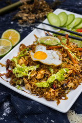 Thai fried rice with egg on top served with vegetables - cucumber and tomato. Traditional asian food served at restaurants and cafes. Vegetarian food