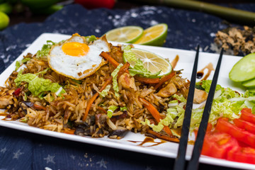 Thai fried rice with egg on top served with vegetables - cucumber and tomato. Traditional asian food served at restaurants and cafes. Vegetarian food
