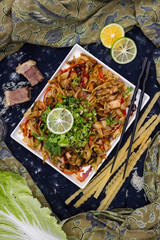 Asian fried noodles with vegetables, prawn and octopus meat cooked in soy sauce. Traditional authentic food in asian cafe or restaurant. Eat with chopsticks