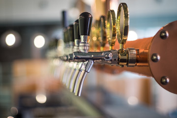 Row of draft beer tab on the top of counter bar in closeup view, time of celebration, selective focus. - obrazy, fototapety, plakaty