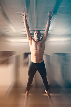 An athelte , 50 Y, is jumping estending legs and arms.