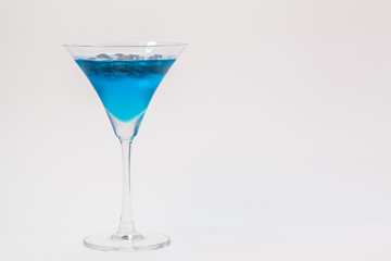 a glass of blueberry in blue water on white background