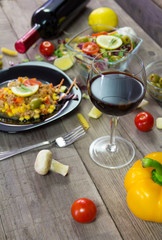 Milanez salat with fresh vegetable, olives, lemon, tomato, papper, garlik, mushrooms and wine in background. Mediterian food