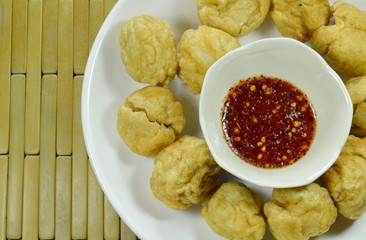  crispy fried fish ball dipping with spicy and sweet sauce cup on plate