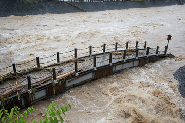 河川の増水で流されそうな橋