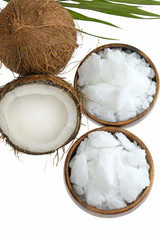 Coconut oil.  natural solid coconut oil in pieces in round wooden bowls and half fresh coconut and a palm leaf isolated on a white background.	